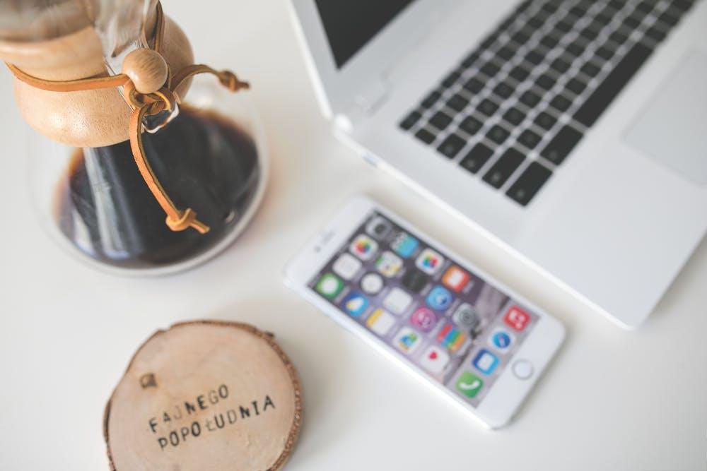 coffee, phone, and a laptop placed on a desk